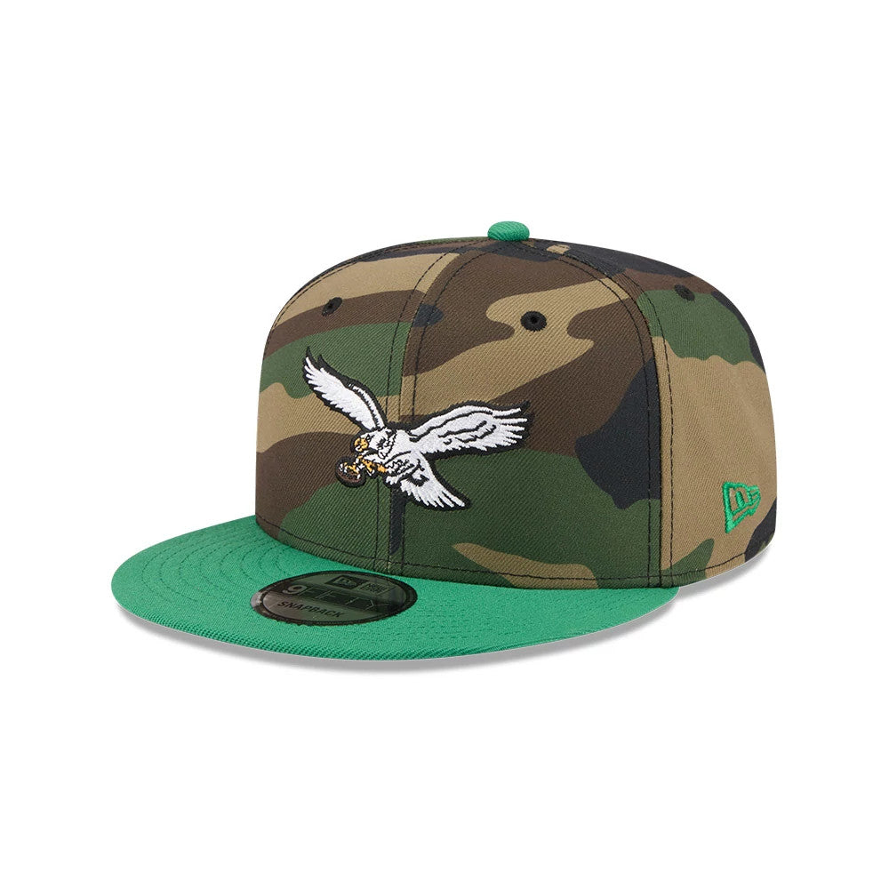 Philadelphia Eagles NFL Camo & Green New Era 9FIFTY Snapback Adjustable Cap, front view showing a raised white and gold eagle logo on the camouflage crown, a flat green visor, and a 9FIFTY size sticker on the top.