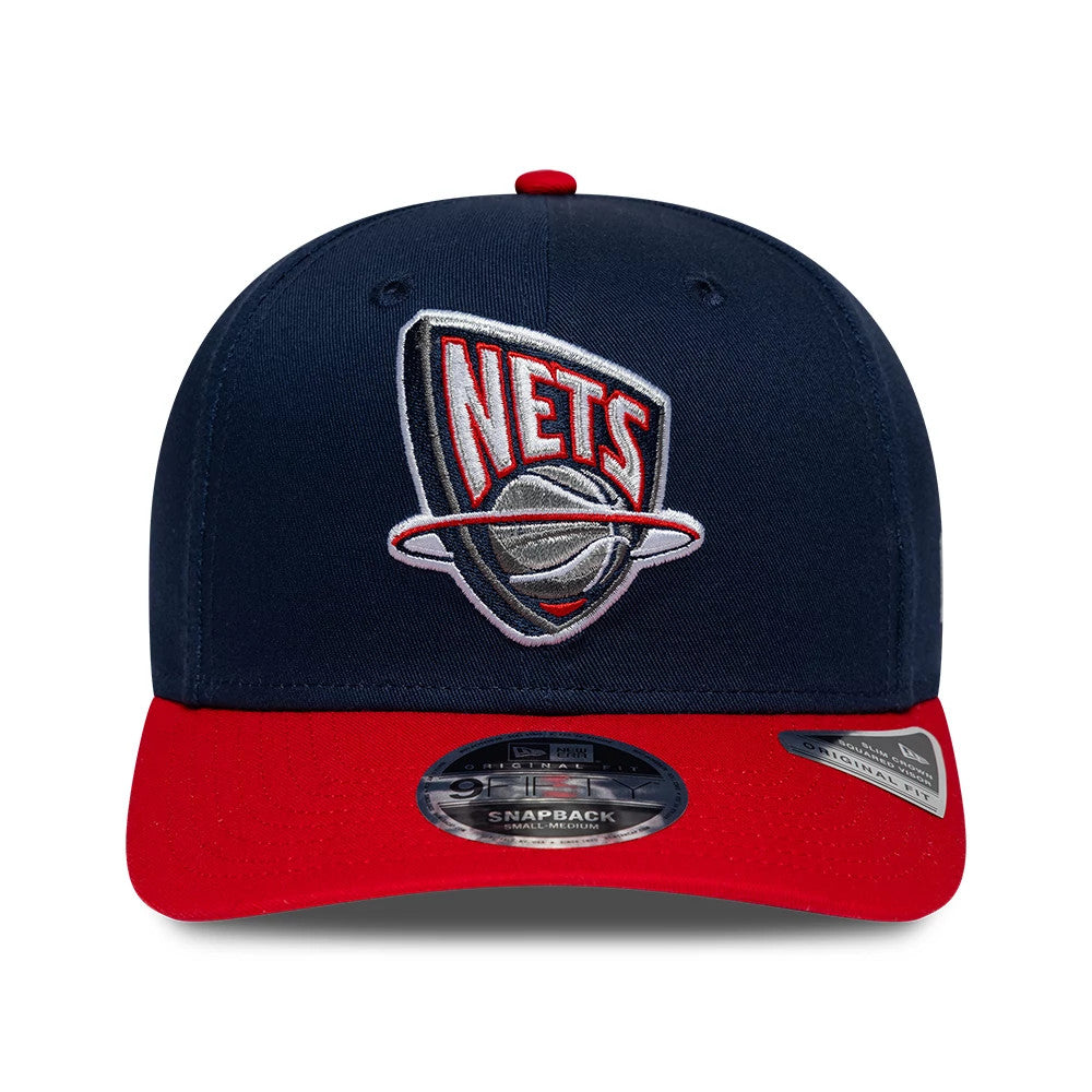 Nets NBA Hardwood Classic Dark Blue New Era 9FIFTY Snapback Adjustable Cap, front view showing raised embroidery of a shield-shaped Nets logo on the structured dark blue crown, red flat visor with a 9FIFTY size sticker, and a red top button.
