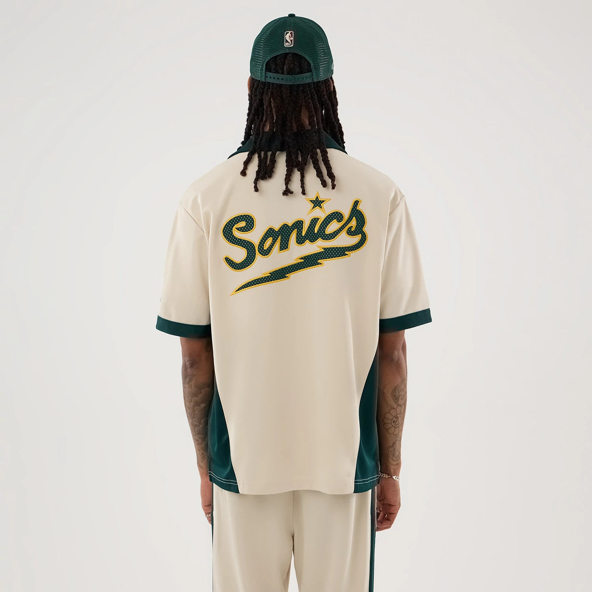 The model is wearing this NBA Hardwood Classic Revere Seattle Supersonics Short Sleeve Shirt in light beige. 2
