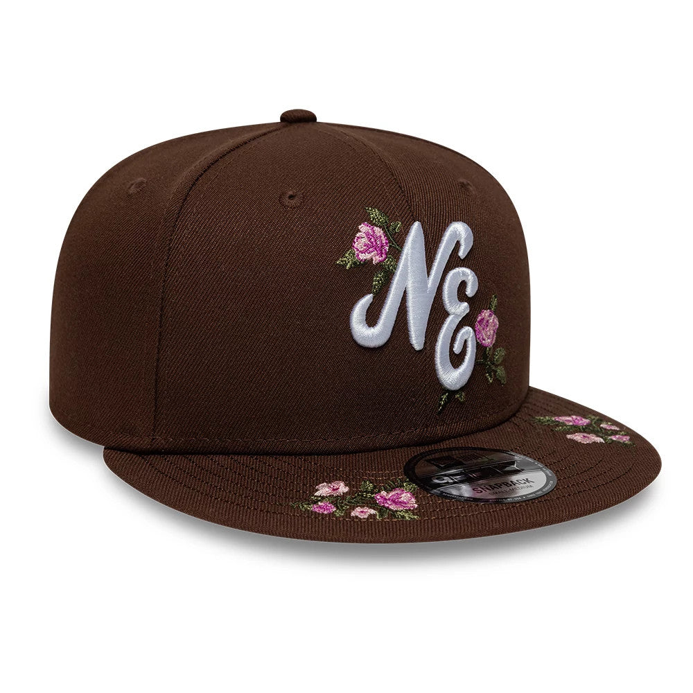 New Era Floral Dark Brown 9FIFTY Snapback Adjustable Cap, front view showing white and pink floral embroidery around the raised NE logo on the front panel, complemented by a matching floral design on the dark brown flat visor with a 9FIFTY size sticker.