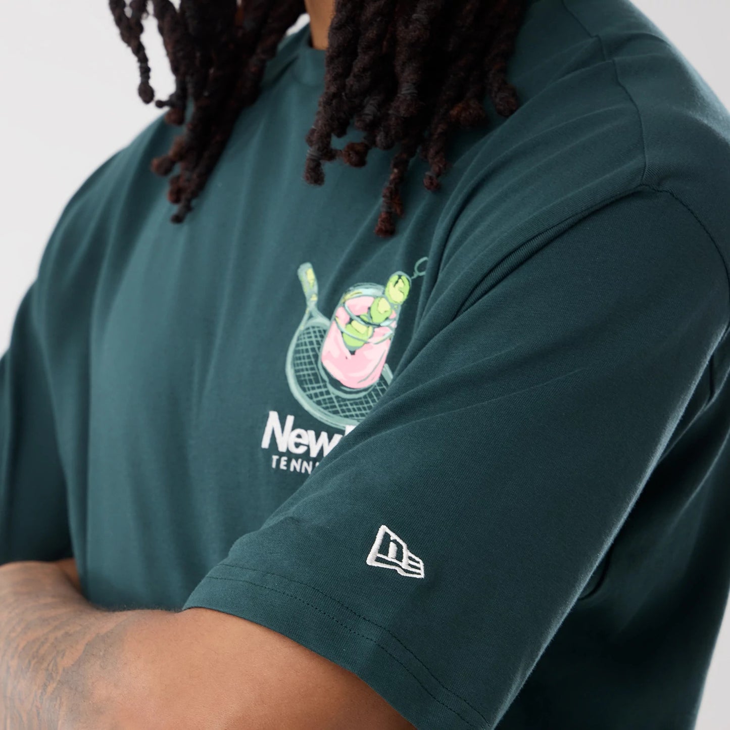 The model is wearing this New Era Tennis Graphic Oversized T-Shirt in dark green. 7