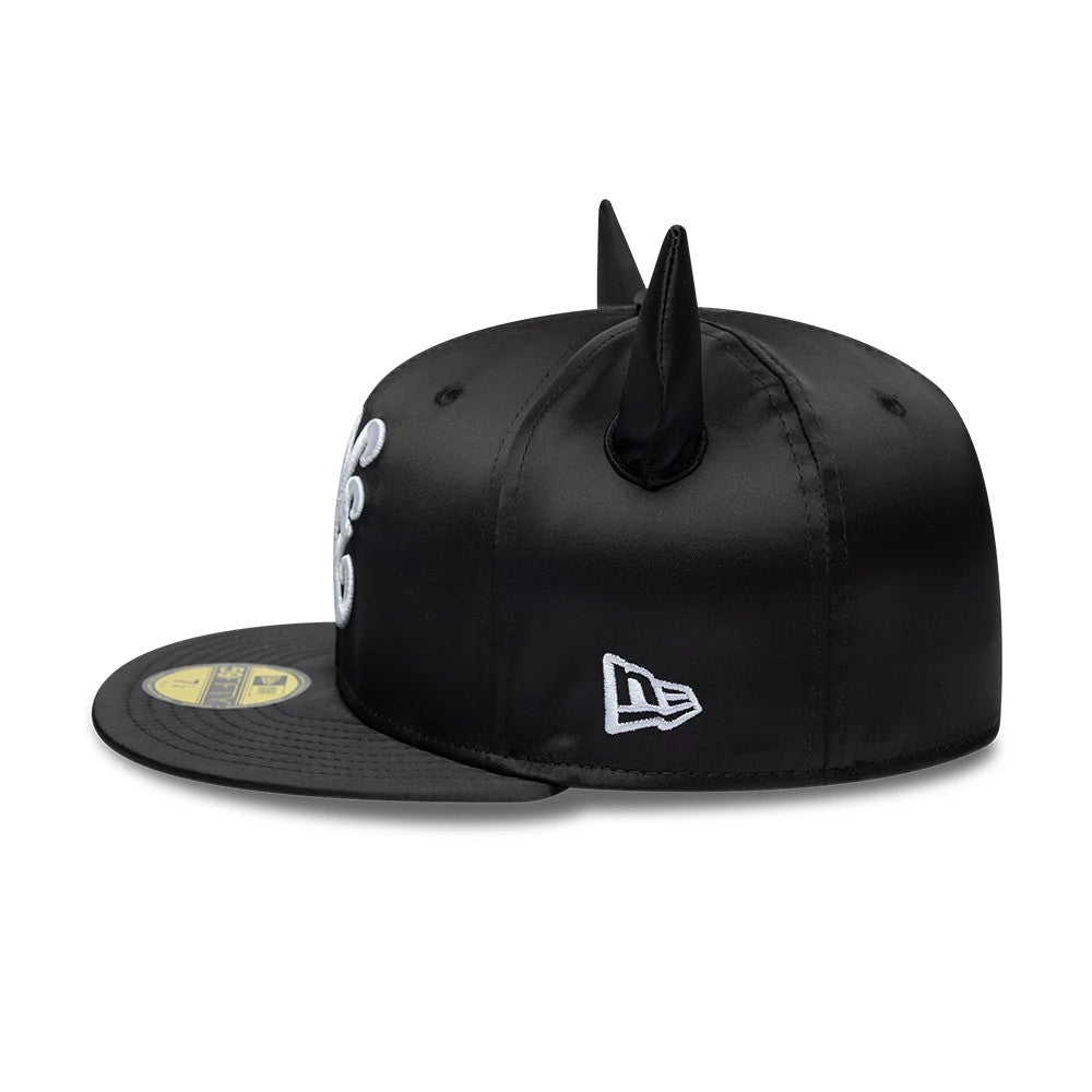 New Era Satin Horn Black 59FIFTY Fitted Cap, side view showing the distinctive black satin finish with horn features on the crown, a white embroidered New Era flag logo on the left side, and a flat black visor with a gold 59FIFTY size sticker.
