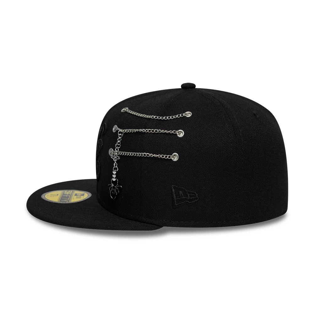 New Era Spider Pin Chain Black 59FIFTY Fitted Cap, side view showing a chrome pin and chain detail across the eyelets on the side panel, black embroidered New Era flag logo on the left side, and black flat visor with gold 59FIFTY size sticker.