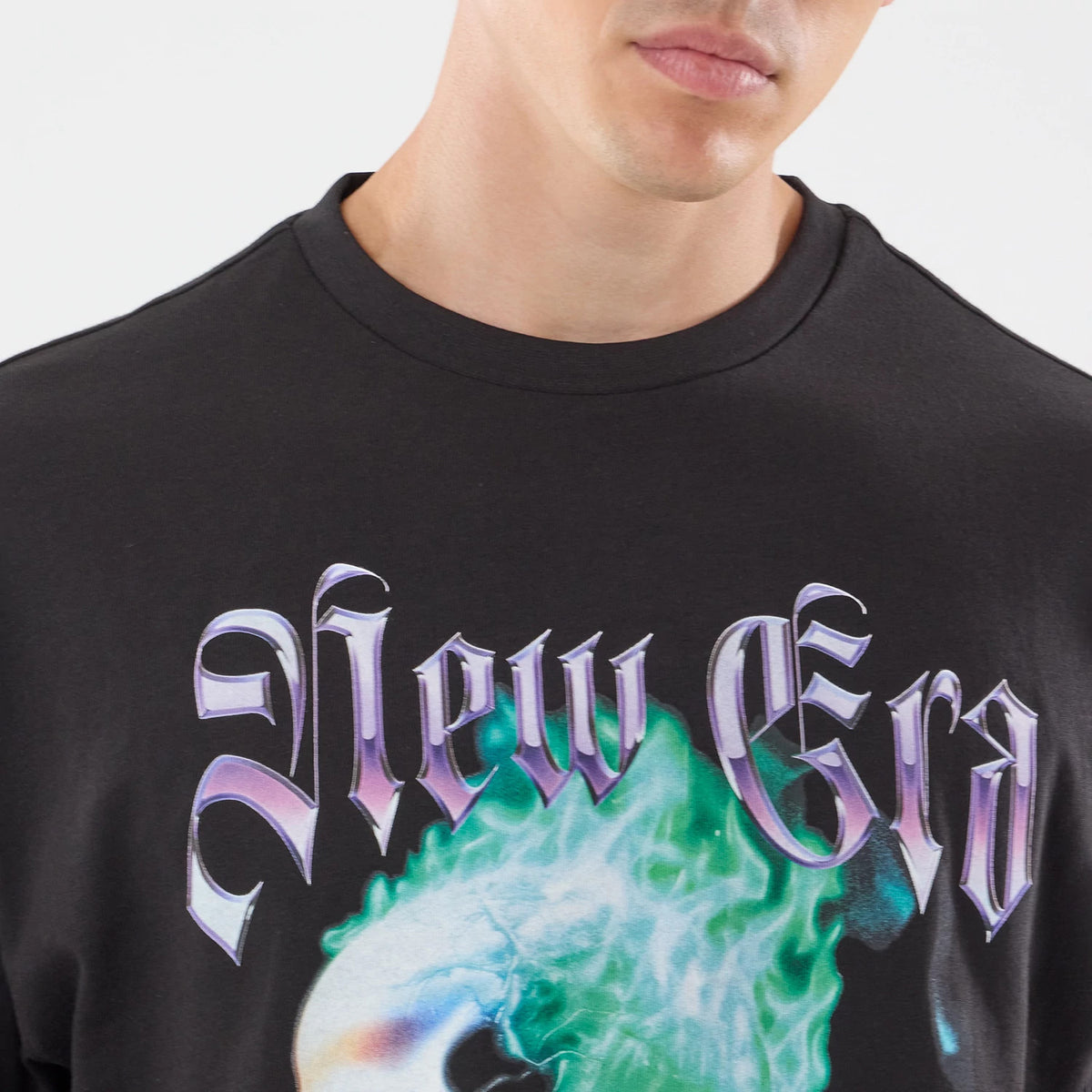 New Era Skull Graphic Oversized Black T-Shirt, front view on-model showing large Gothic-style New Era text in purple across the chest, a vivid skull graphic underneath with a mix of green and blue hues, and a simple round neckline.