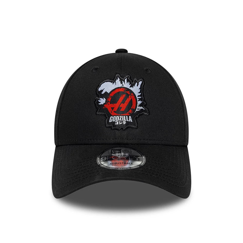 Godzilla X TGR Haas F1 Black New Era 9FORTY Adjustable Cap, front view showing a red and grey embroidered logo on the structured black crown and a curved black visor with a 9FORTY size sticker.