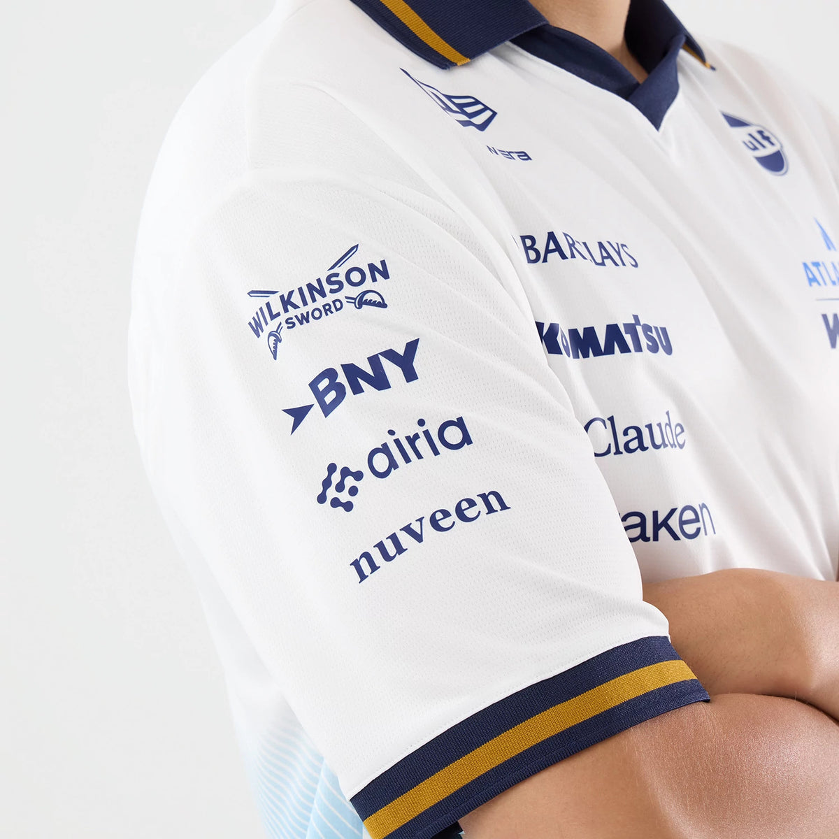 New Era Williams Spain Race Special White T-Shirt, three-quarter view showing the navy Wilkinson Sword, BNY, and other logos printed on the right sleeve, alongside a contrasting navy and yellow striped cuff and a New Era logo near the collar.
