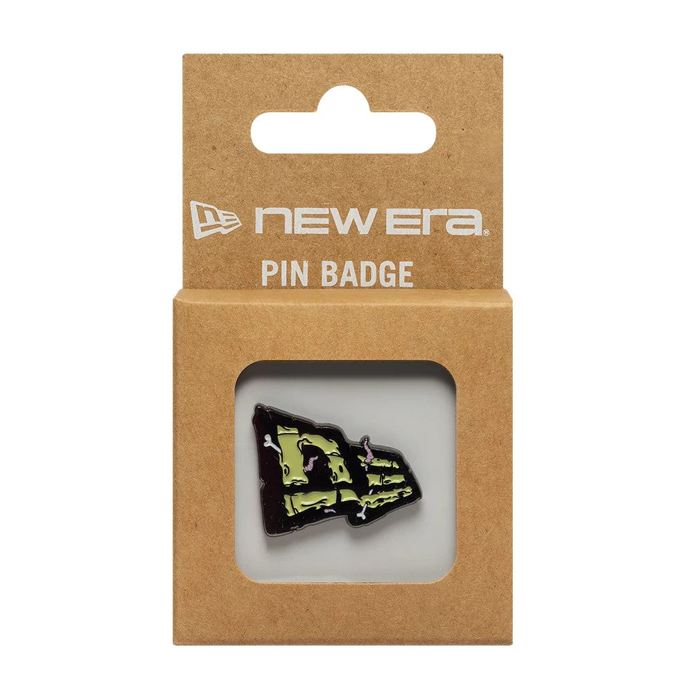 New Era Halloween Worm Grey Pin Badge, front view showing a pin badge with a zombie-themed design featuring a grey and green logo with worm details, encased in a brown cardboard packaging with a New Era logo and 'PIN BADGE' text above.