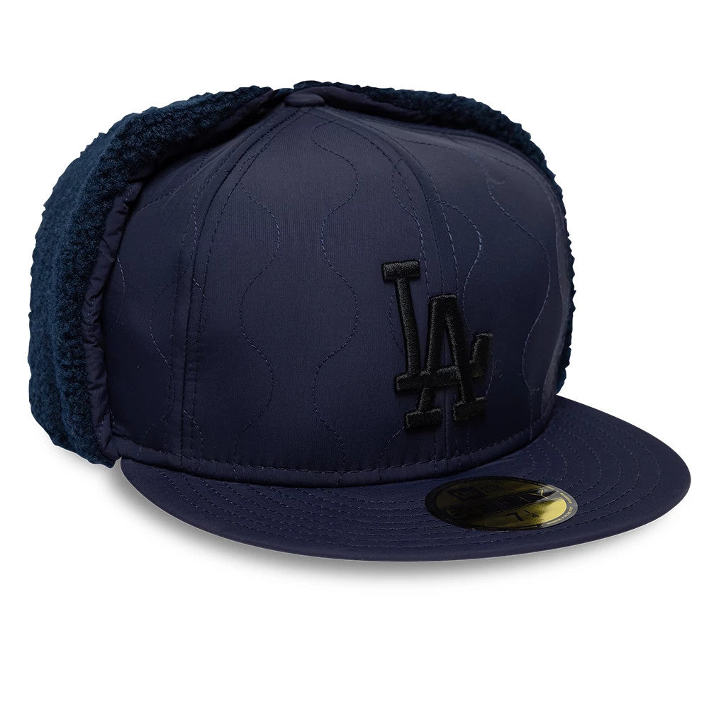 LA Dodgers MLB Quilted Navy New Era Dogear 59FIFTY Fitted Cap, three-quarter view showing the black embroidered LA logo on the front panel, quilted navy fabric with dogear flaps, and the gold 59FIFTY size sticker on the flat visor.