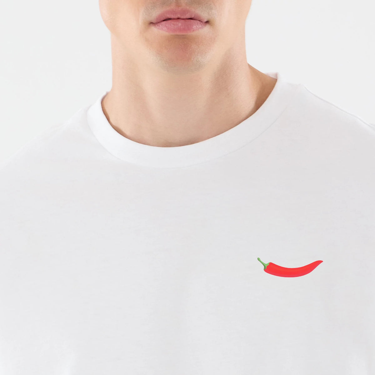 New Era Carlos Sainz Team Fifty5 White Oversized T-Shirt, front view on a model showcasing a minimalistic red chilli pepper graphic printed on the left chest area, with a classic white crew neck and a relaxed fit on the upper body.