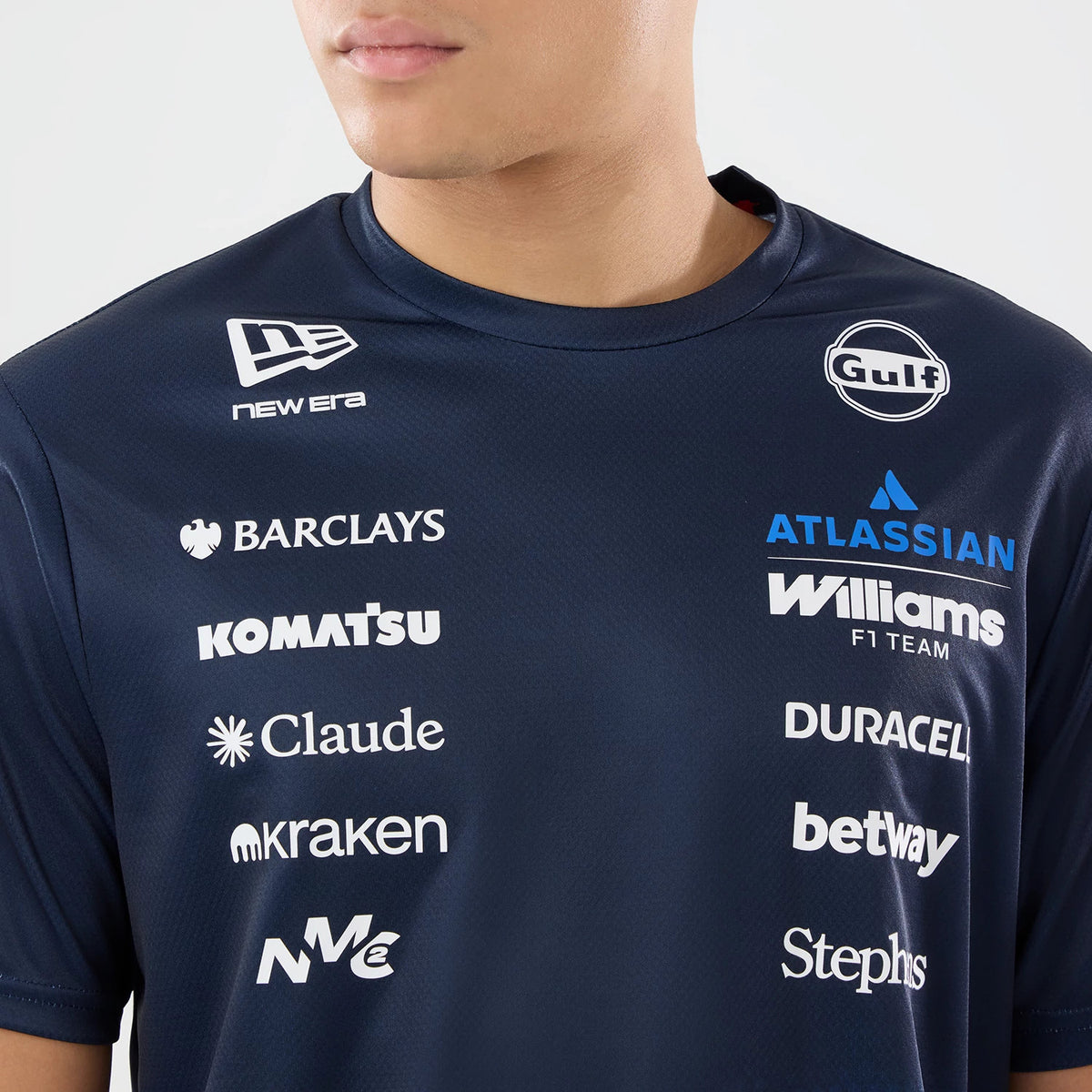 New Era Williams Singapore Navy Tech T-Shirt, front view on a model featuring multiple printed sponsor logos across the chest including Barclays, Komatsu, and Claude, with the New Era logo prominently printed near the left shoulder.
