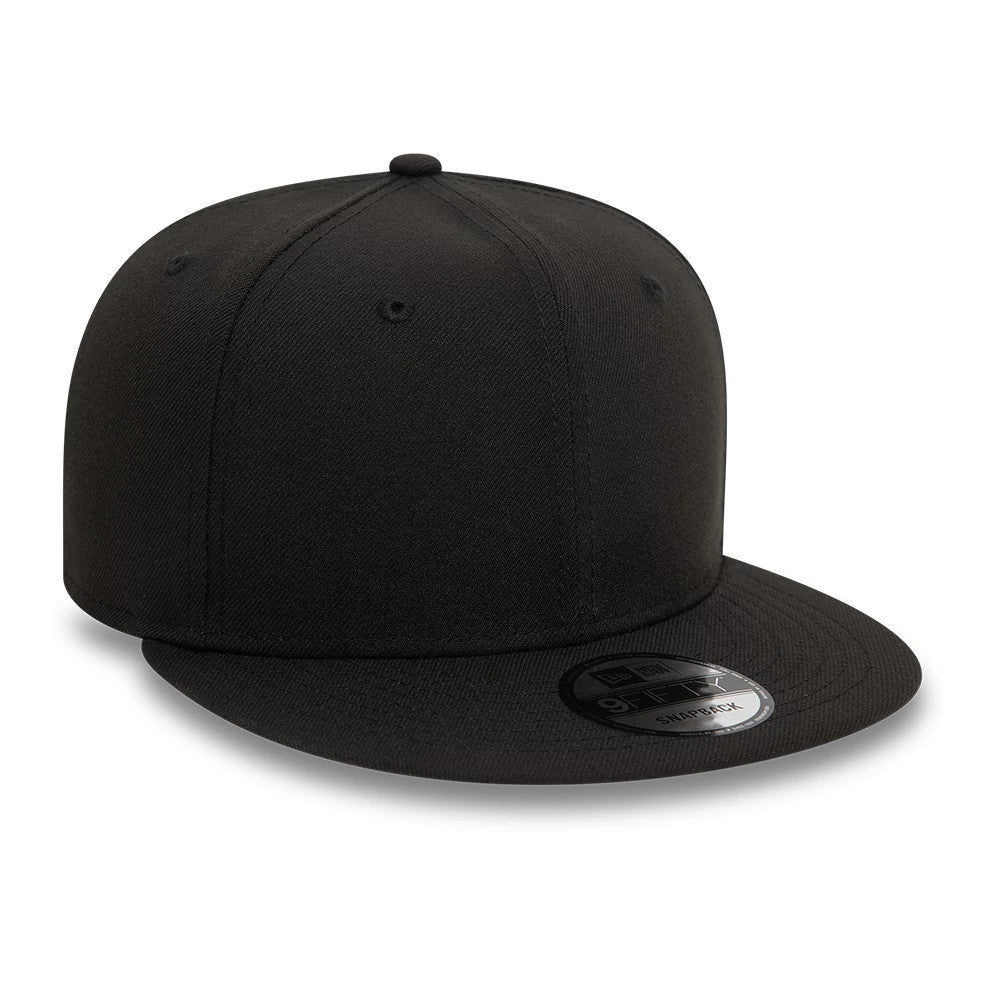 New Era Essential Black New Era 9FIFTY Snapback Cap, front view showing a structured black crown with six black eyelets, a flat black visor with a 9FIFTY size sticker, and a black top button.