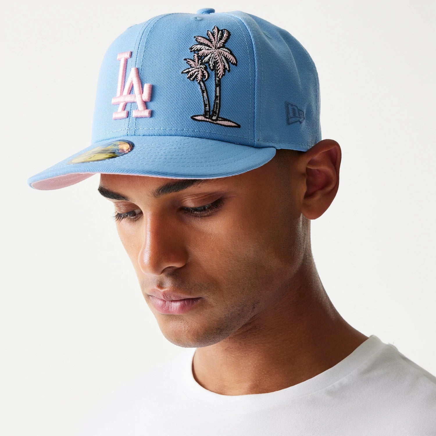 LA Dodgers Palm Taco Blue New Era 59FIFTY Cap, on-model front view showing the prominent pink LA logo on the front panel, palm tree graphic on the right side, and a 59FIFTY size sticker on the pale blue visor.