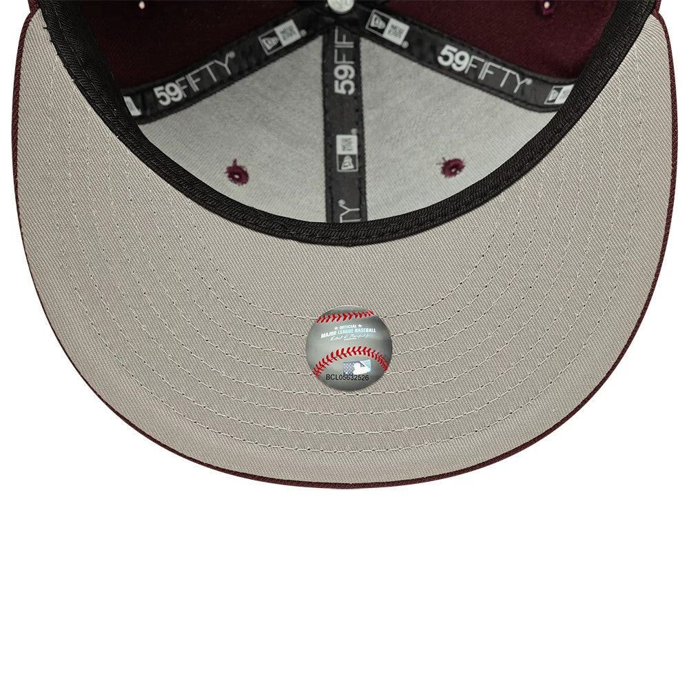 New York Yankees MLB Dark Purple New Era 59FIFTY Fitted Cap, inside view showing the grey undervisor with a baseball-shaped authenticity sticker, black inner taping with 59FIFTY branding, and burgundy eyelet stitching on the crown.