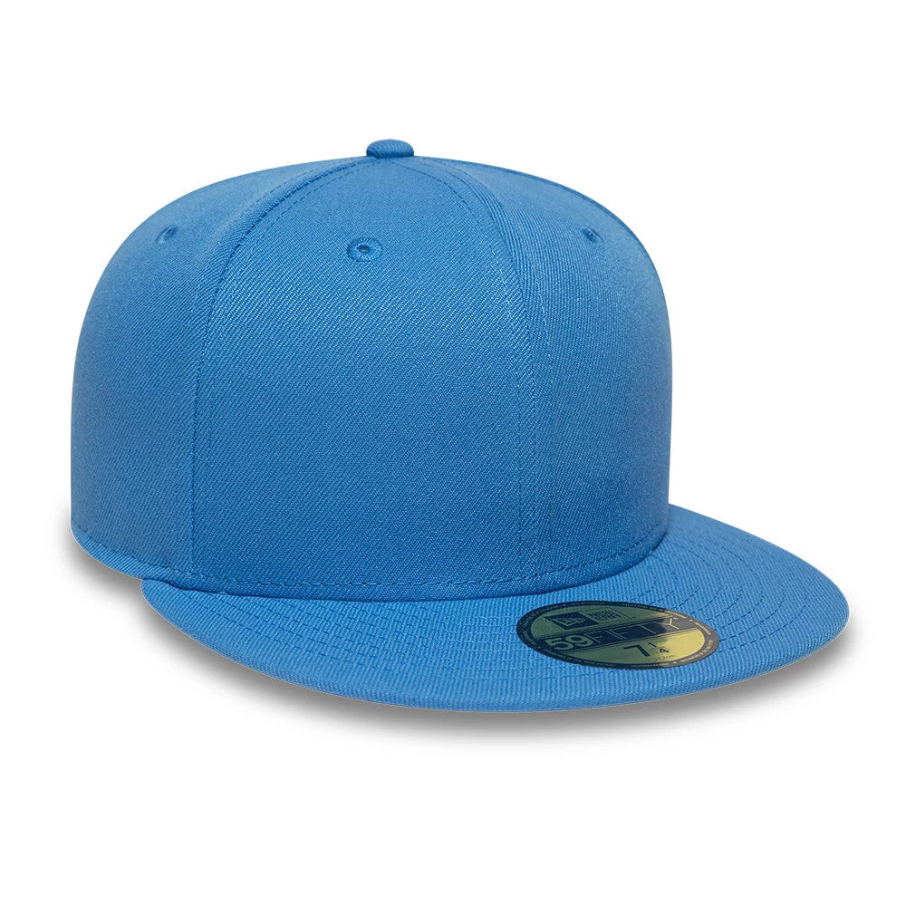 New Era Blue 59FIFTY Fitted Cap, three-quarter view showing the plain blue front panels and matching flat visor, with a gold 59FIFTY size sticker on the visor, and a matching top button and eyelets completing the design.
