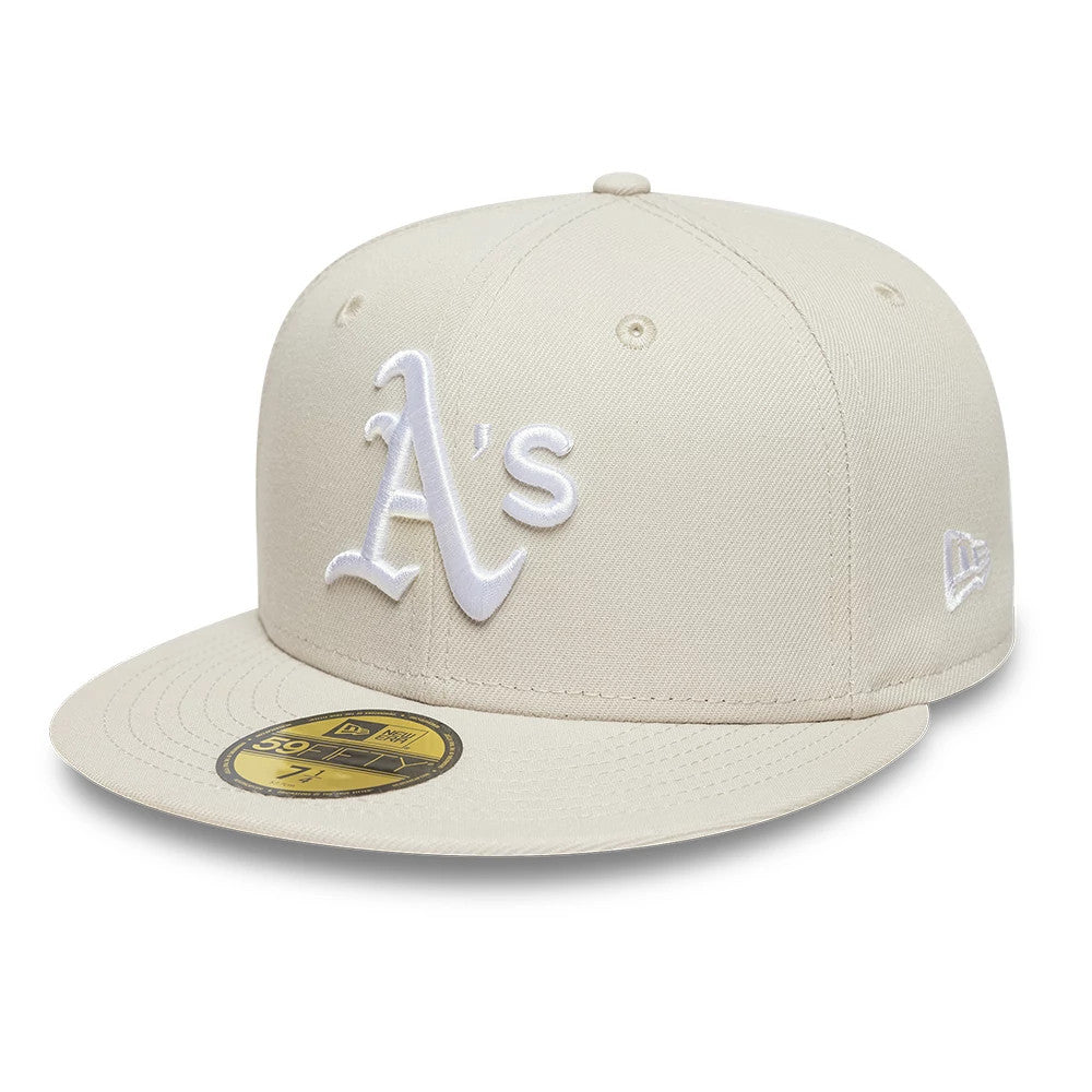 Athletics MLB Beige New Era 59FIFTY Fitted Cap, three-quarter view showing the white raised embroidered A's logo on the front panel, with a matching New Era flag logo on the left side and a gold 59FIFTY size sticker on the pale beige visor.