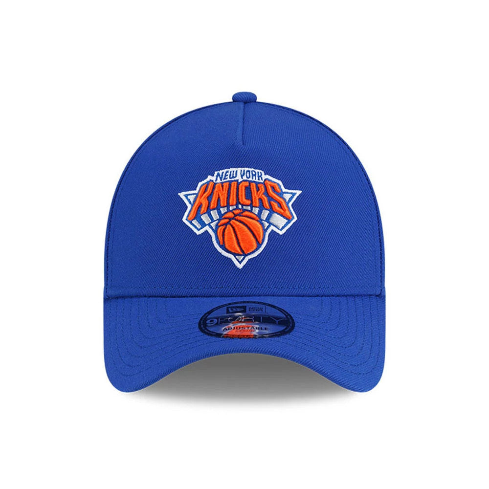 New York Knicks NBA Champs 2025 - 2026 Blue New Era 9FORTY A-Frame Adjustable Cap, front view showing the team logo with orange and white embroidery centred on the structured blue crown, and a 9FORTY size sticker on the pre-curved visor.