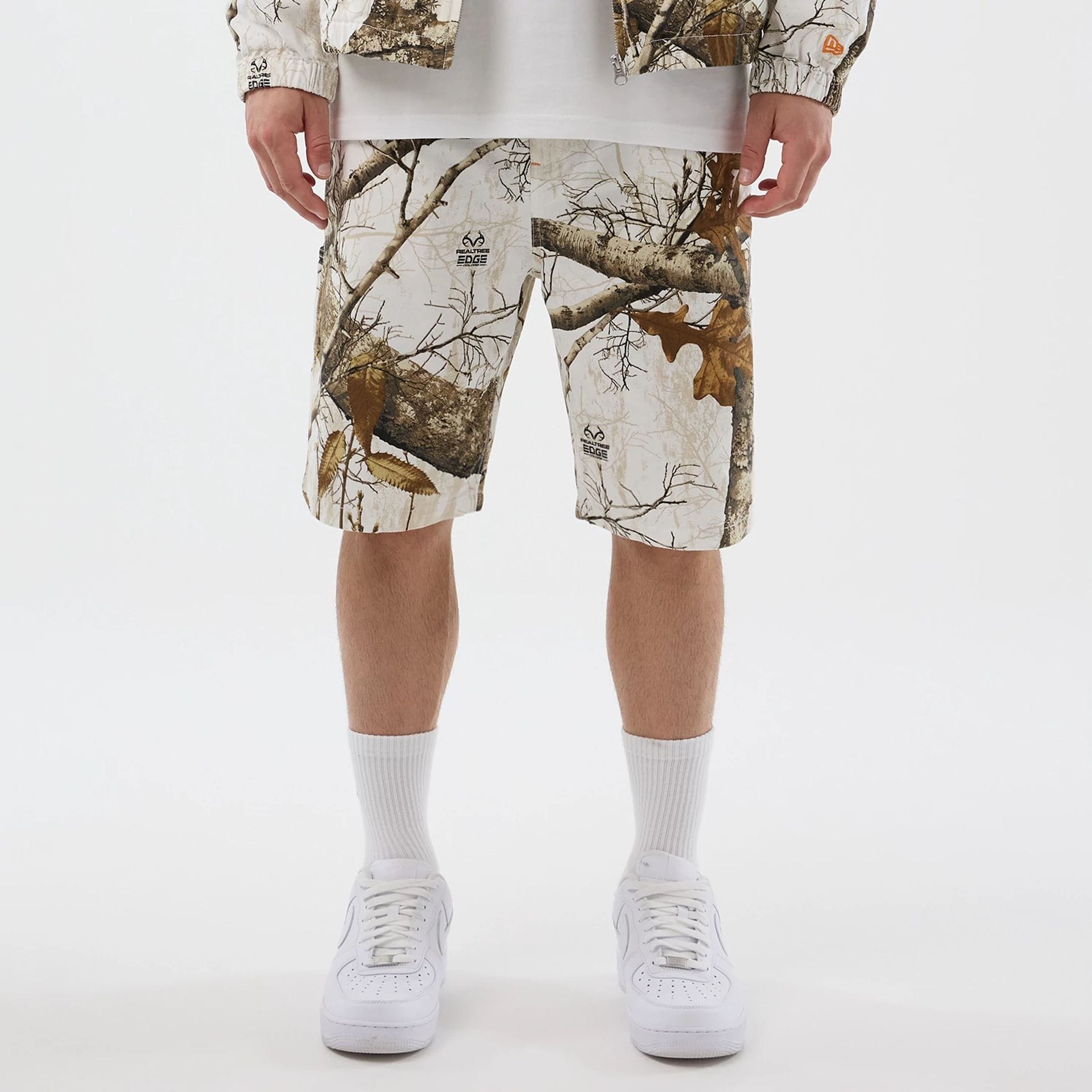 The Male model is wearing  New Era Earthy Skin Real Tree Snow Oversized Shorts  1