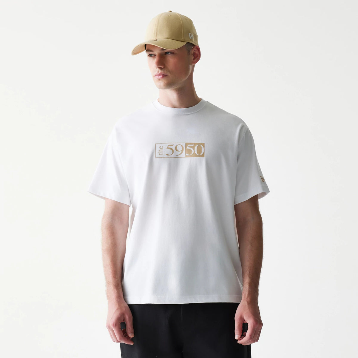 59FIFTY Fitted Cap Description Graphic White T-Shirt, on-model view showing the shirt's central chest design with "the 5950" in beige, worn by a person in a beige cap with a small raised New Era logo on the side.