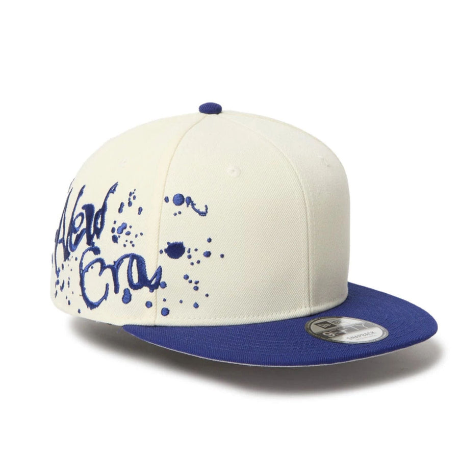 This is a New Era Dripping Emblem Cream 9FIFTY Snapback Adjustable Cap 1