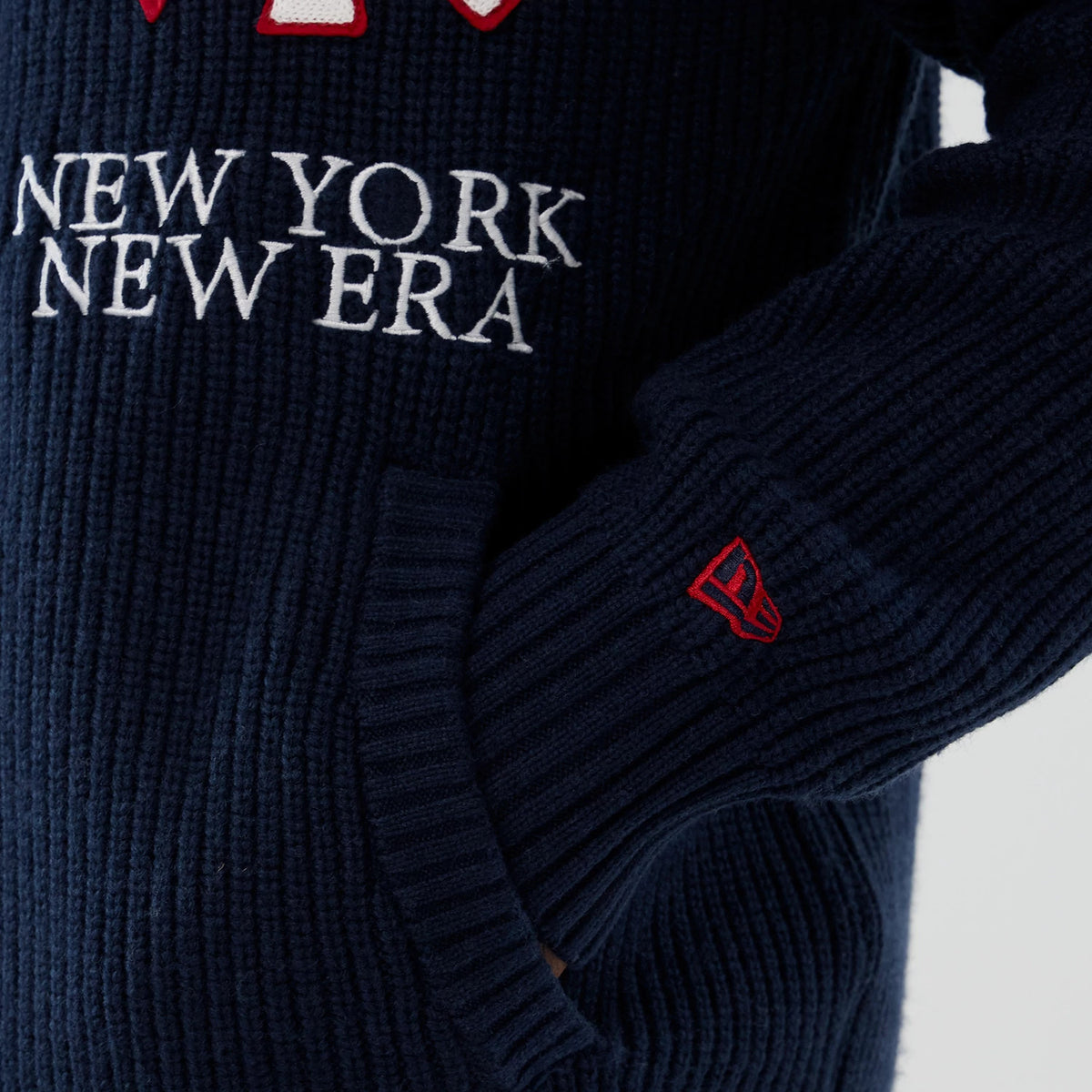 New York Yankees MLB Navy Cardigan, close-up showing New York New Era white embroidery on the navy ribbed texture, red embroidered New Era flag logo on the sleeve, and front pocket detail.