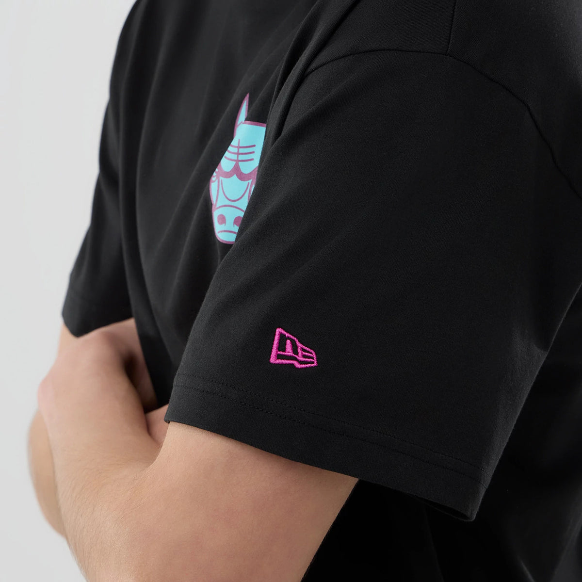 Chicago Bulls NBA Neon Light Black T-Shirt, side view showing a black short-sleeved design with a neon blue Bulls graphic on the chest and a raised pink New Era logo embroidered on the arm near the sleeve hem.