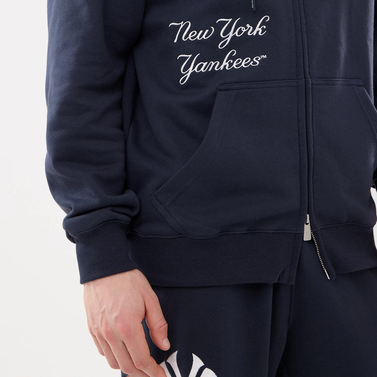 New York Yankees MLB Comfort Navy 2 Way Full Zip Hoodie, front view showing the navy fabric with white embroidered "New York Yankees" script on the chest, a full zip down the middle and a large kangaroo pocket at the front.