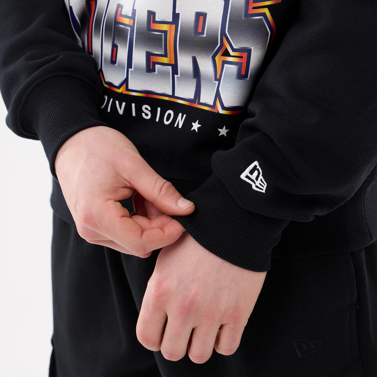 LA Dodgers MLB Retro Black Oversized Crew Neck Sweater, close-up showing the embroidered New Era flag logo on the ribbed cuff of the left sleeve, with large Dodgers lettering across the chest and a soft black fabric.