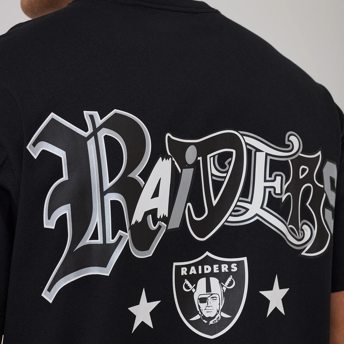 Las Vegas Raiders NFL Word Art Black T-Shirt, rear view showing large graphic word art "Raiders" in white and grey on the back, with the Raiders shield logo and two stars below in white.