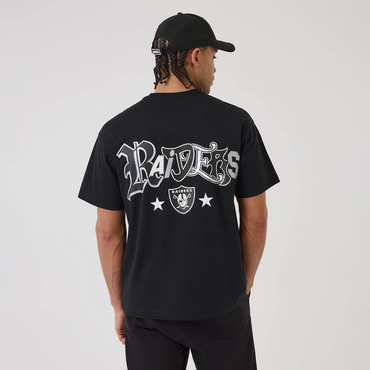 Las Vegas Raiders NFL Word Art Black T-Shirt, on-model view showing the bold "Raiders" text across the back in large grey letters with a debossed emblem below, two stars flanking the emblem on the black fabric.