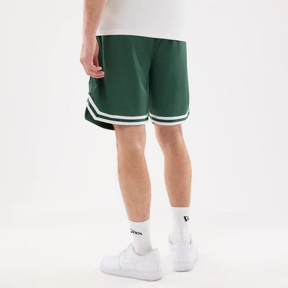 LA Dodgers MLB Comfort Dark Green Oversized Shorts, on-model rear view of the dark green shorts with white striped edging near the hem, worn by a person standing in white trainers and socks, showcasing the relaxed oversized fit.
