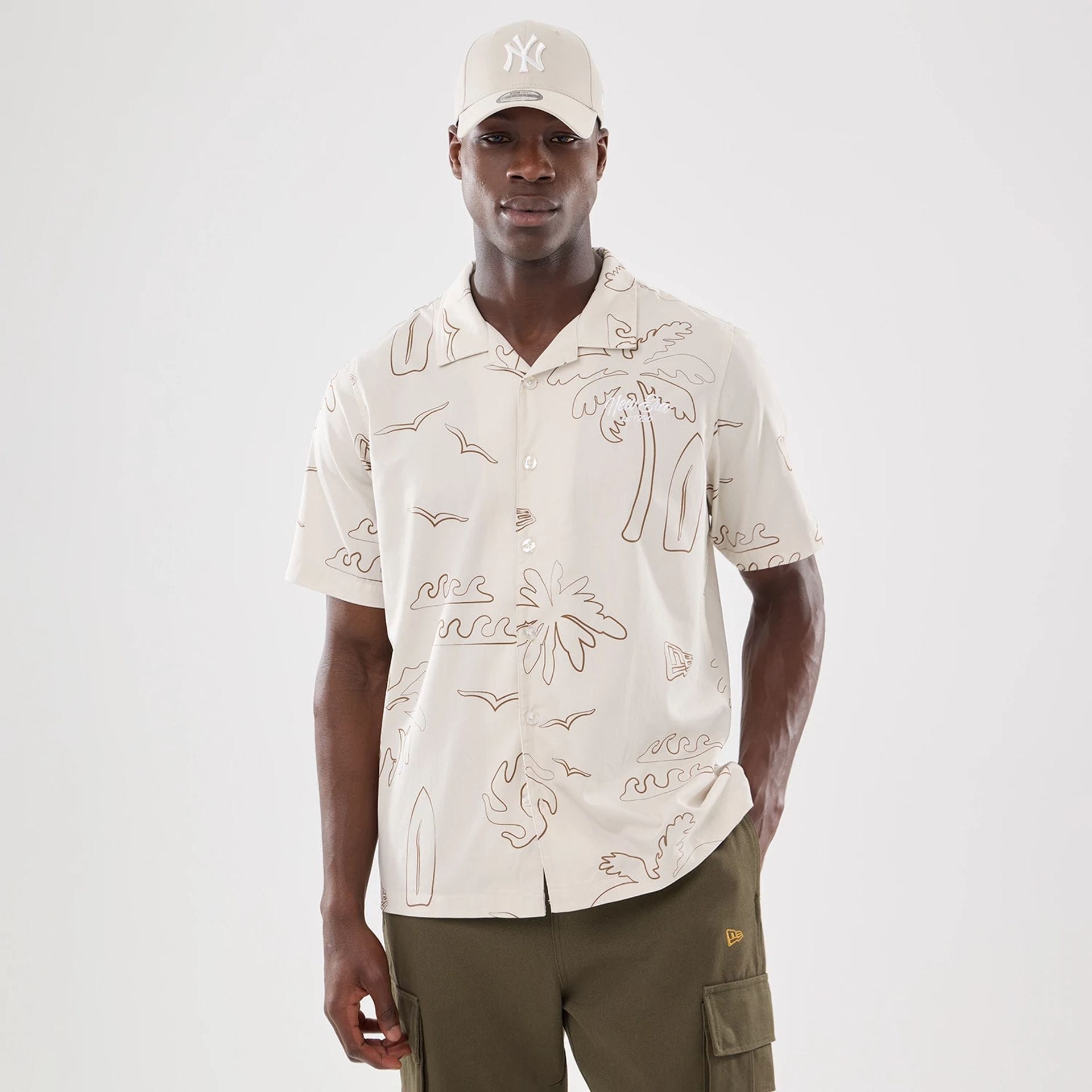 The model is wearing this New Era Resort Short Sleeve Shirt in natural. 1