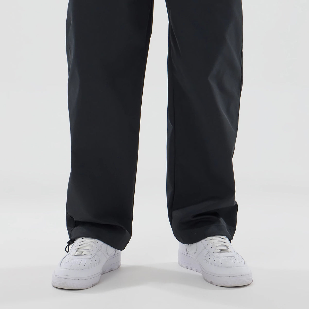 New Era NEC Logo Black Straight Leg Joggers, front view on a model showing the relaxed fit around the legs and paired with white trainers, emphasising the versatile and casual style of the joggers.