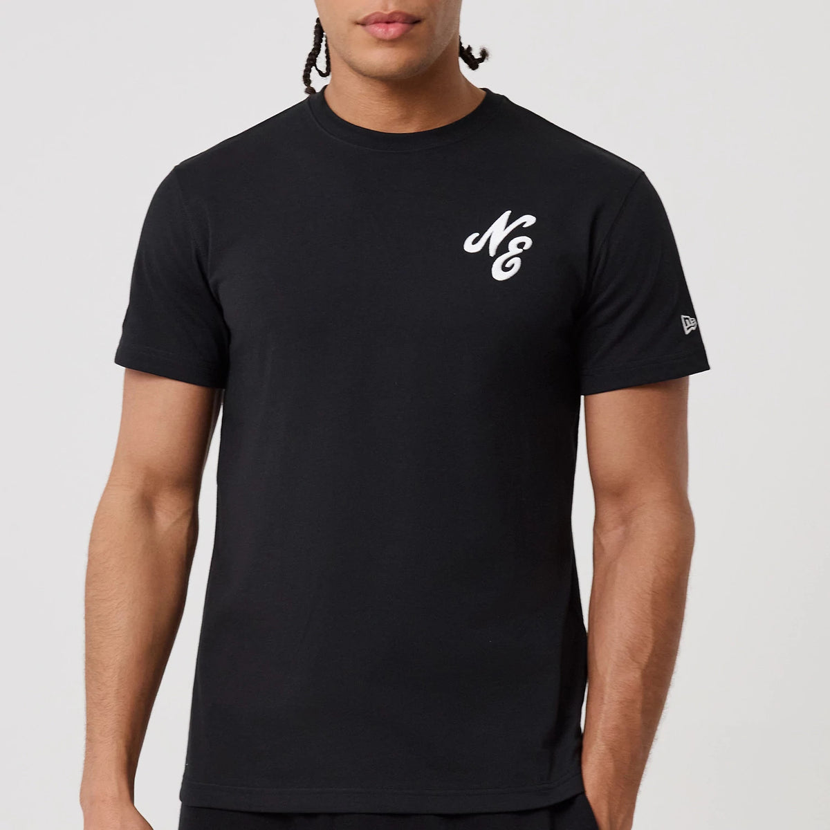 New Era Sakura Black T-Shirt, front view showing a plain black shirt with a white raised "NE" logo on the left chest and a small raised New Era logo on the left sleeve near the hem.