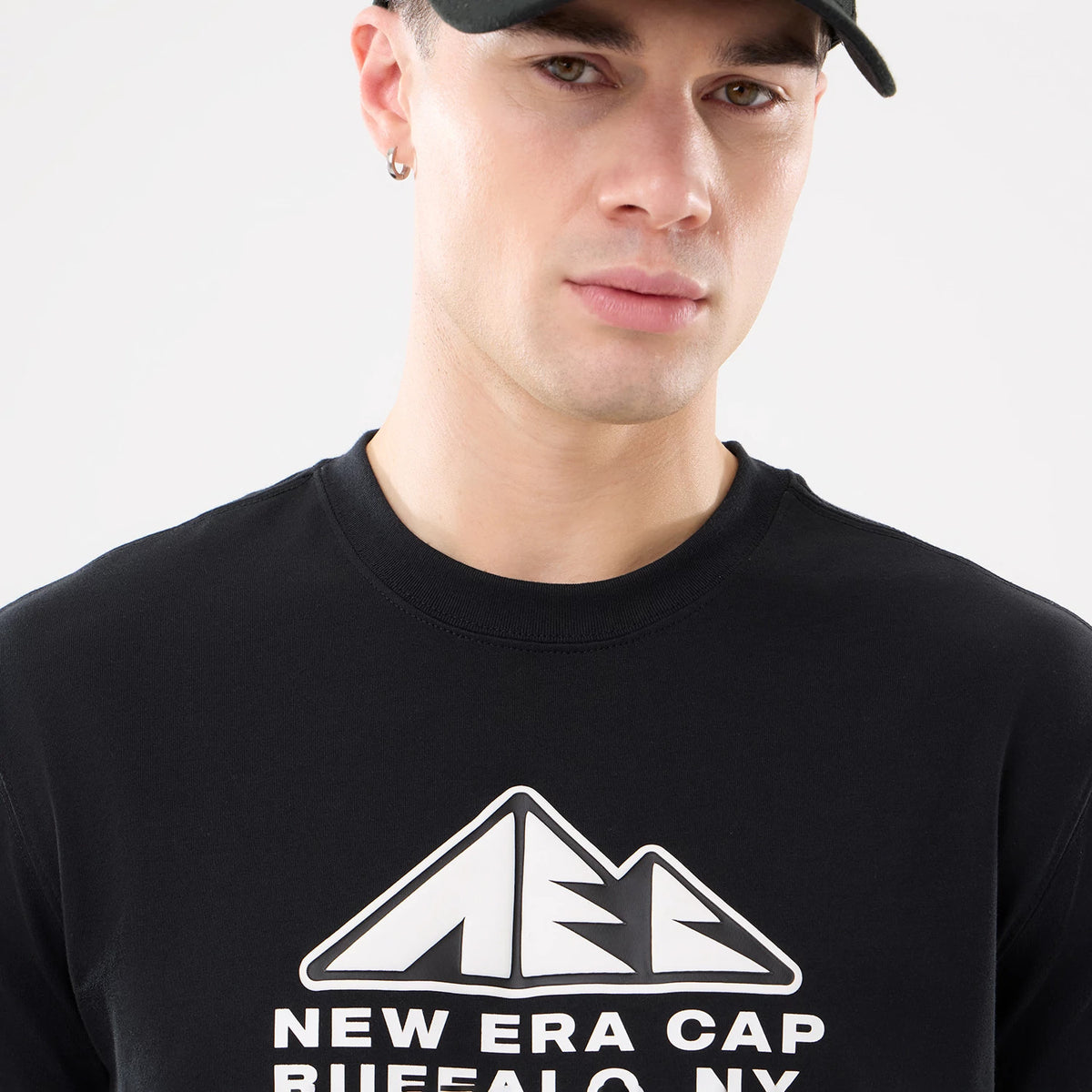 New Era Outdoor Mountain Black T-Shirt, front view showing a raised white mountain logo design centred on the chest, with the words "New Era Cap Buffalo NY" below, on a plain black fabric.