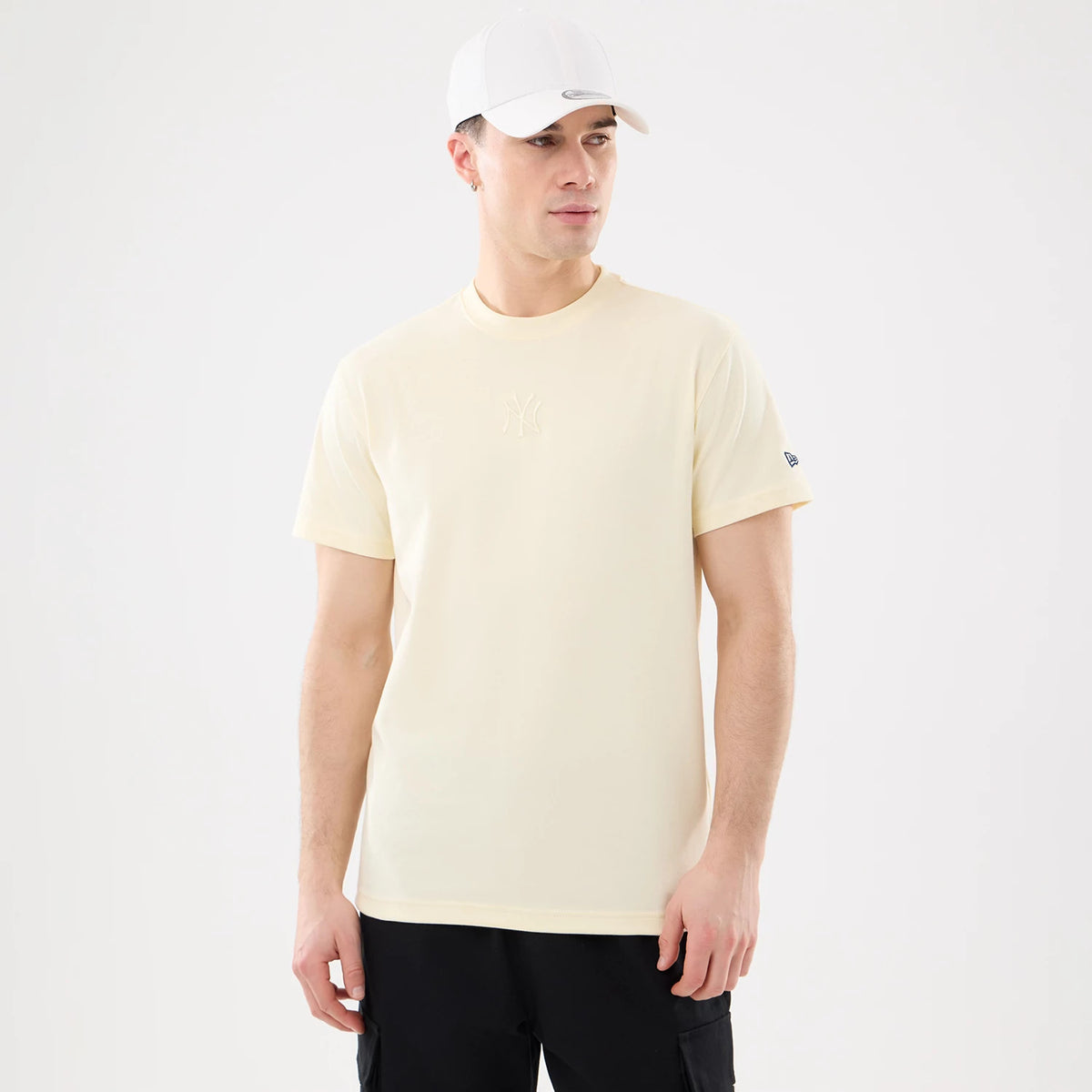 New York Yankees MLB Cartoon Cream T-Shirt, on-model view showing the cream-coloured t-shirt with a debossed New York Yankees logo on the chest and a raised New Era logo on the left sleeve.