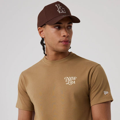 The model is wearing this New Era Script Graphic T-Shirt in Beige. 3