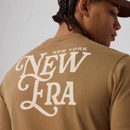The model is wearing this New Era Script Graphic T-Shirt in Beige. 4