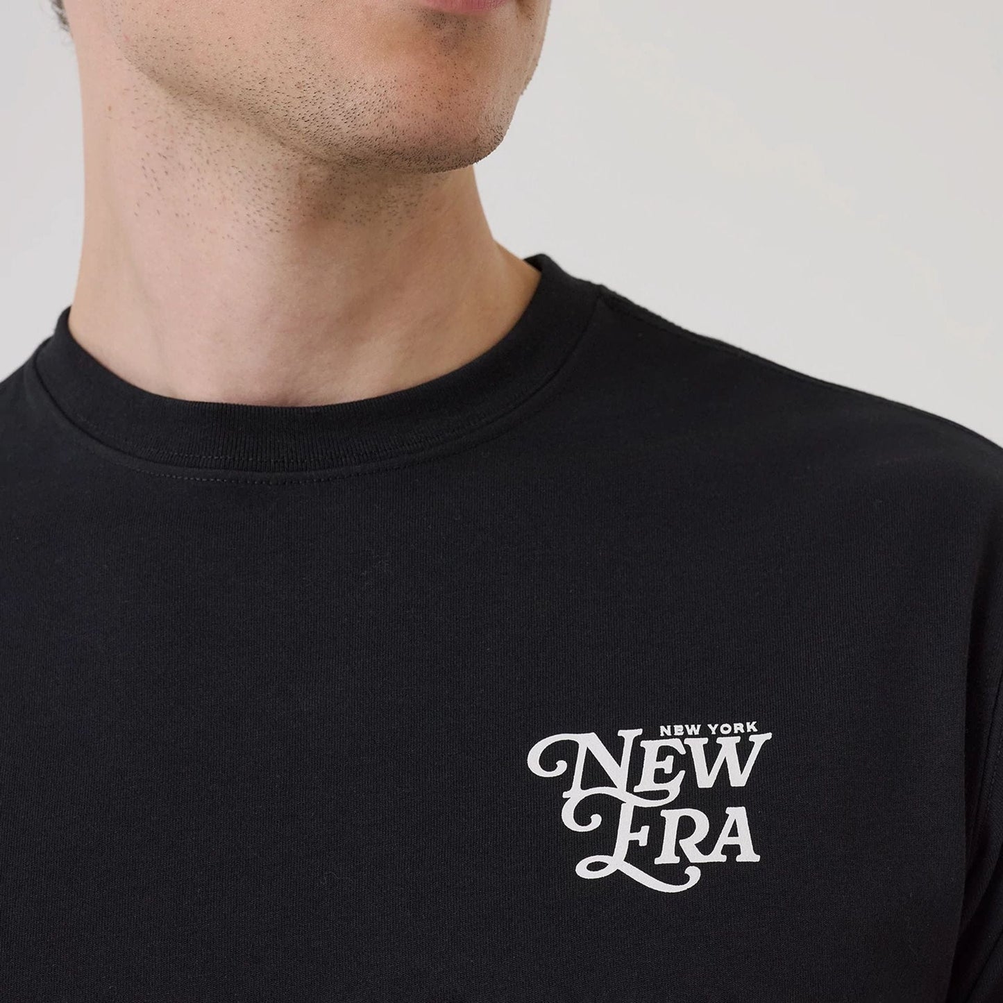 The model is wearing this New Era Script Graphic T-Shirt in black. 6