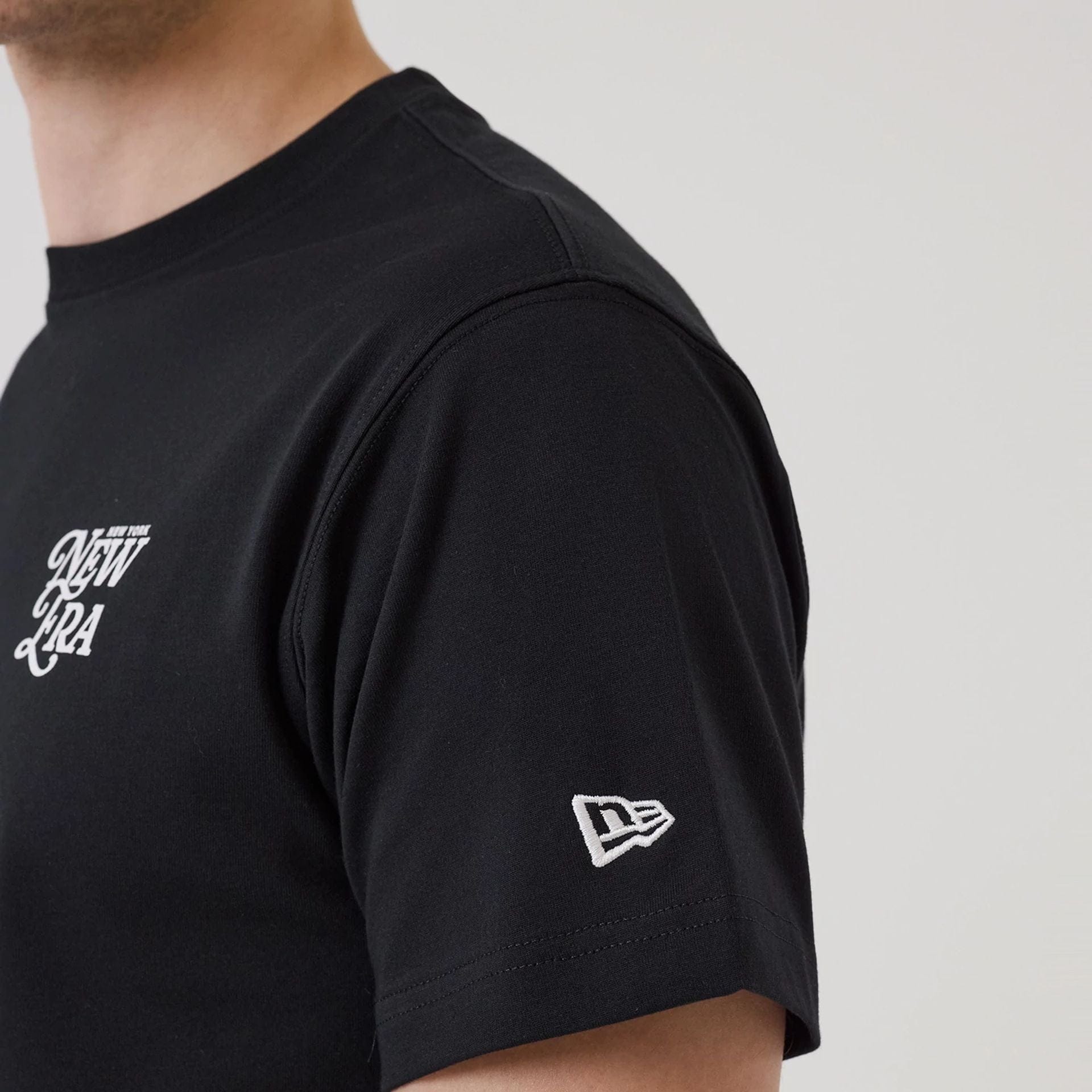 The model is wearing this New Era Script Graphic T-Shirt in black. 7