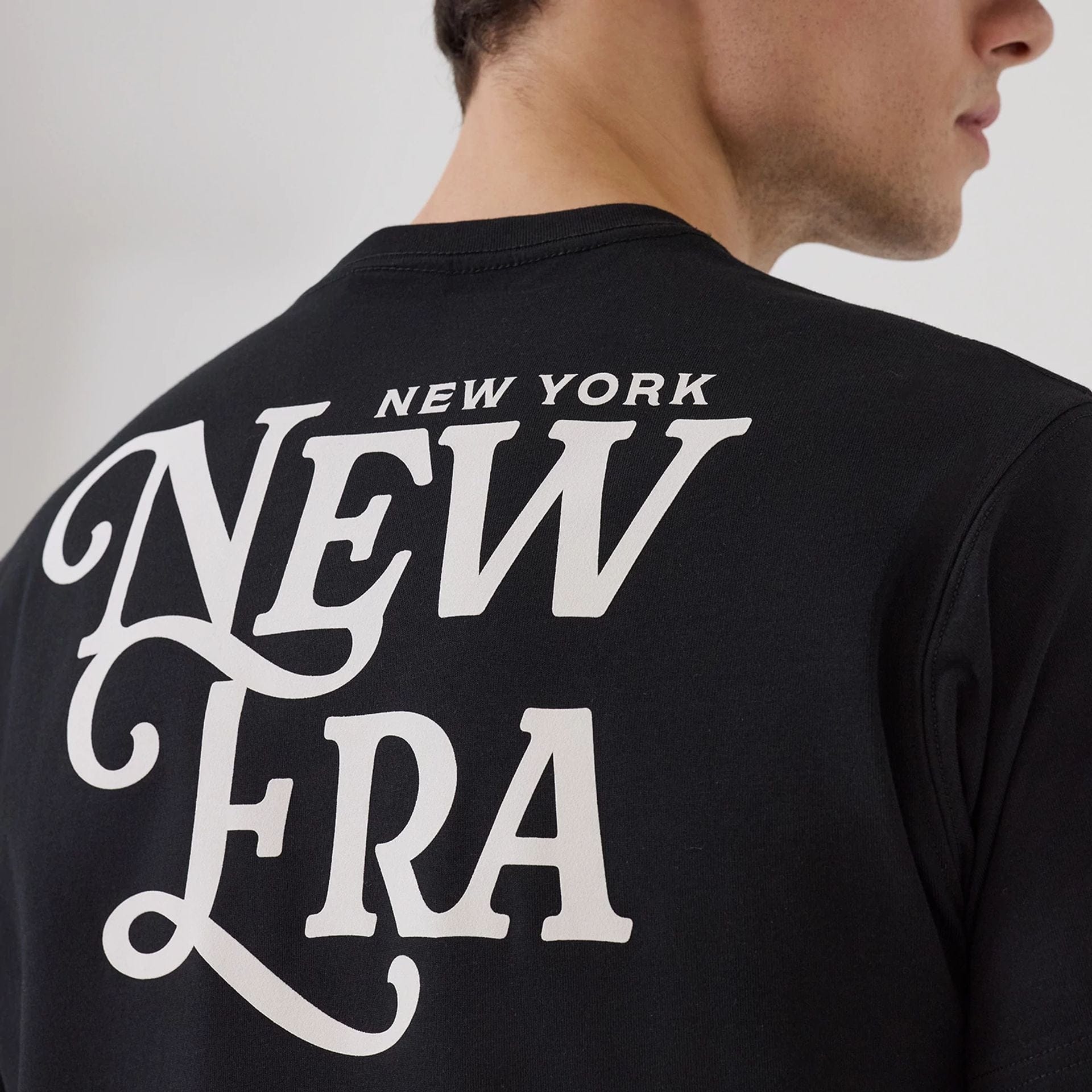 The model is wearing this New Era Script Graphic T-Shirt in black. 3