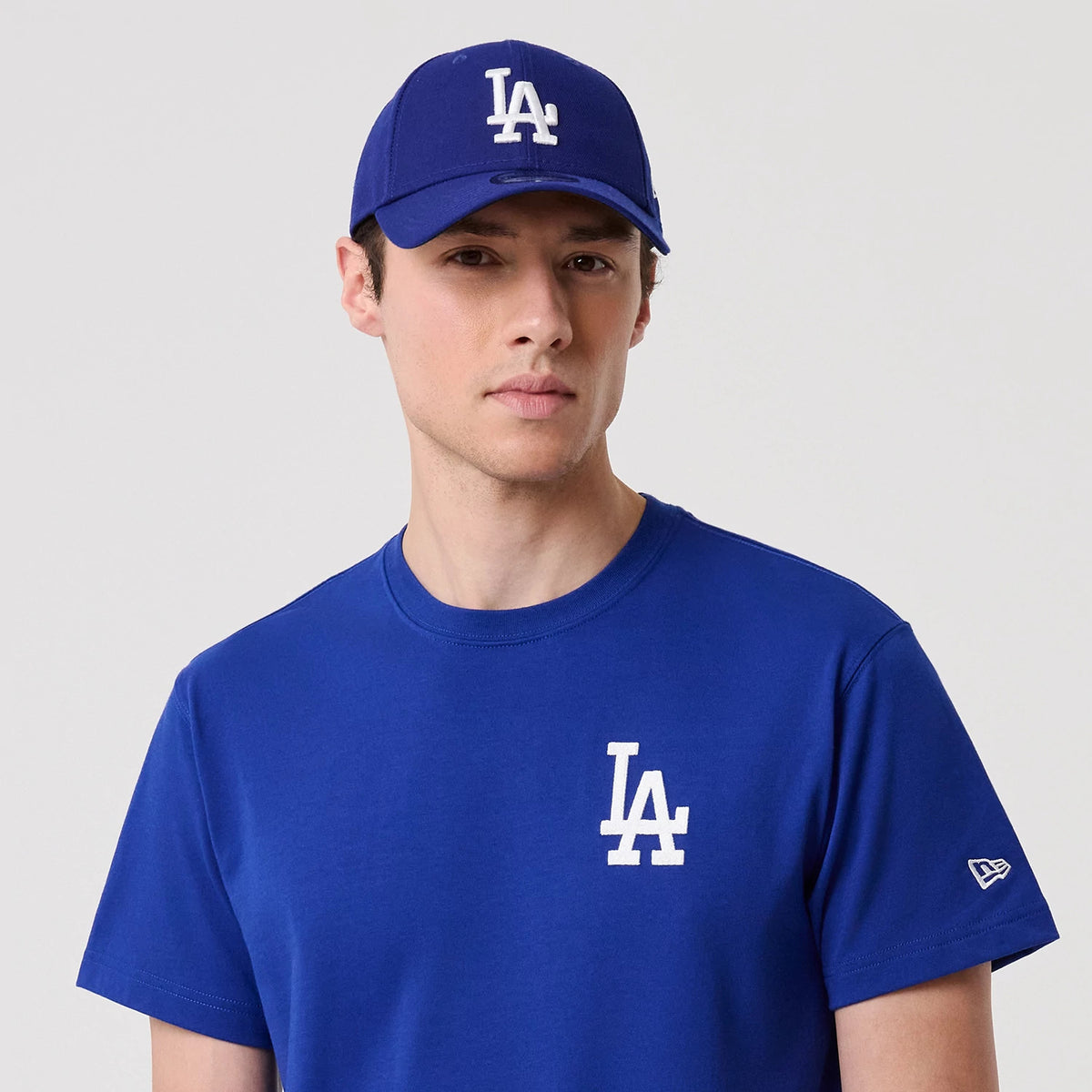 LA Dodgers MLB Banana Graphic Bright Blue T-Shirt, on-model view showing the bright blue T-shirt with a white LA logo on the chest, a matching debossed LA logo on the blue cap worn by the model and the New Era logo on the sleeve.