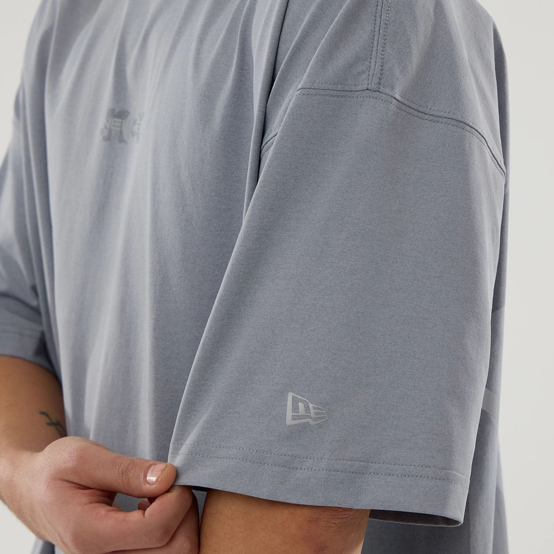 The model is wearing this New Era NEC Logo Oversized T-Shirt in grey. 5