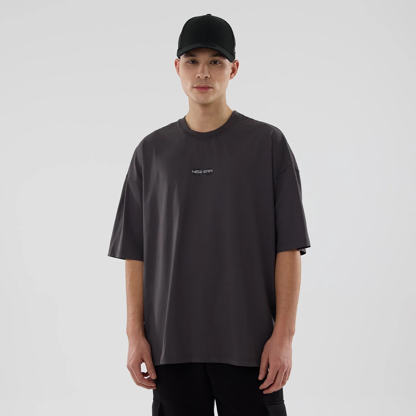The model is wearing this New Era NEC Logo Oversized T-Shirt in black. 1