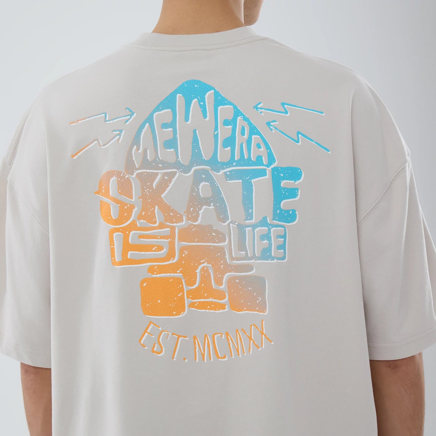 The model is wearing this New Era Skate Is Life Graphic Oversized T-Shirt in Cream. 4