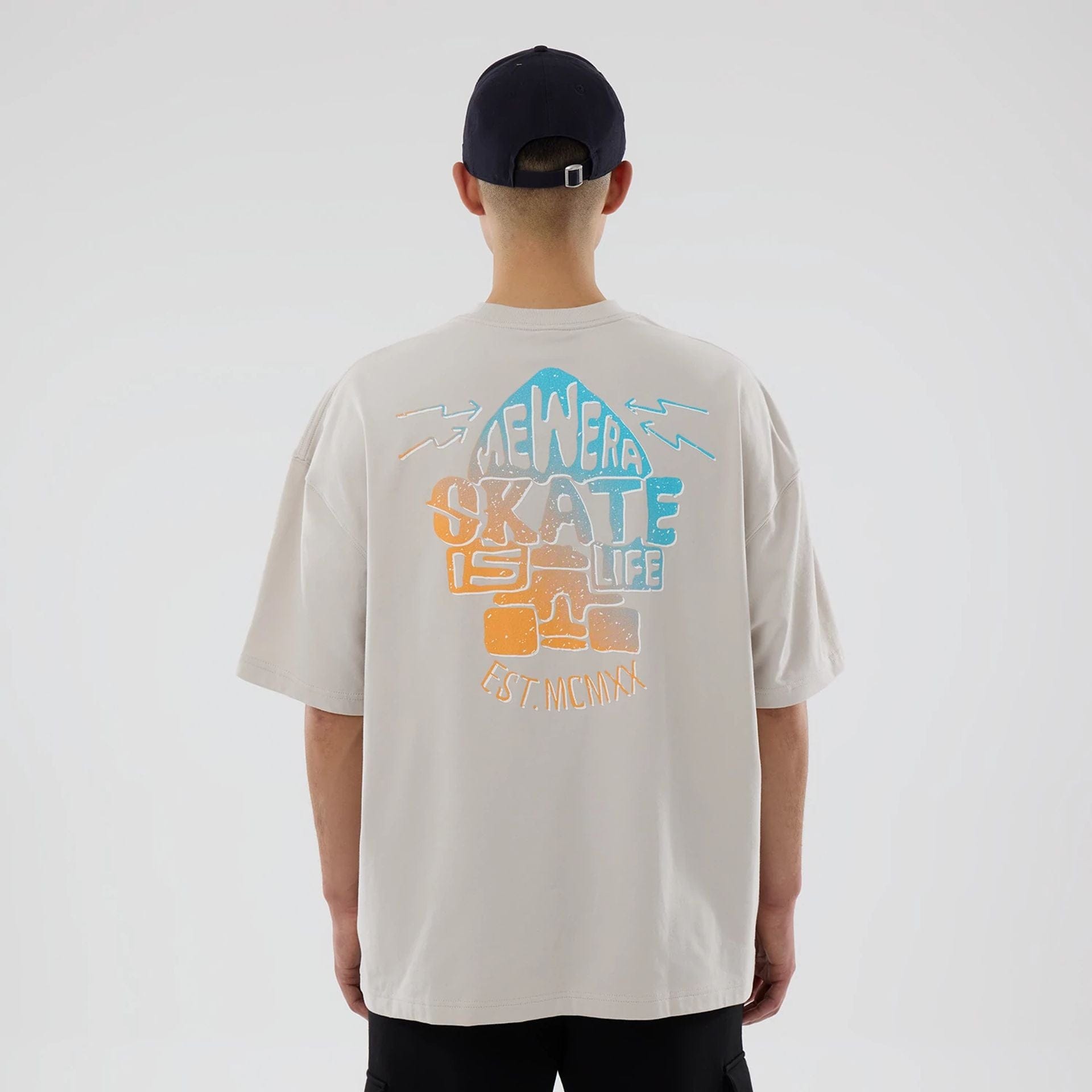 The model is wearing this New Era Skate Is Life Graphic Oversized T-Shirt in Cream. 2
