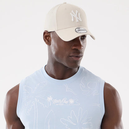 New Era Resort Blue Tank Top, on-model front view featuring embroidered palm tree and New Era est. 1920 text on the chest, paired with a cream New York Yankees cap with raised white logo and 9FORTY size sticker on the visor.