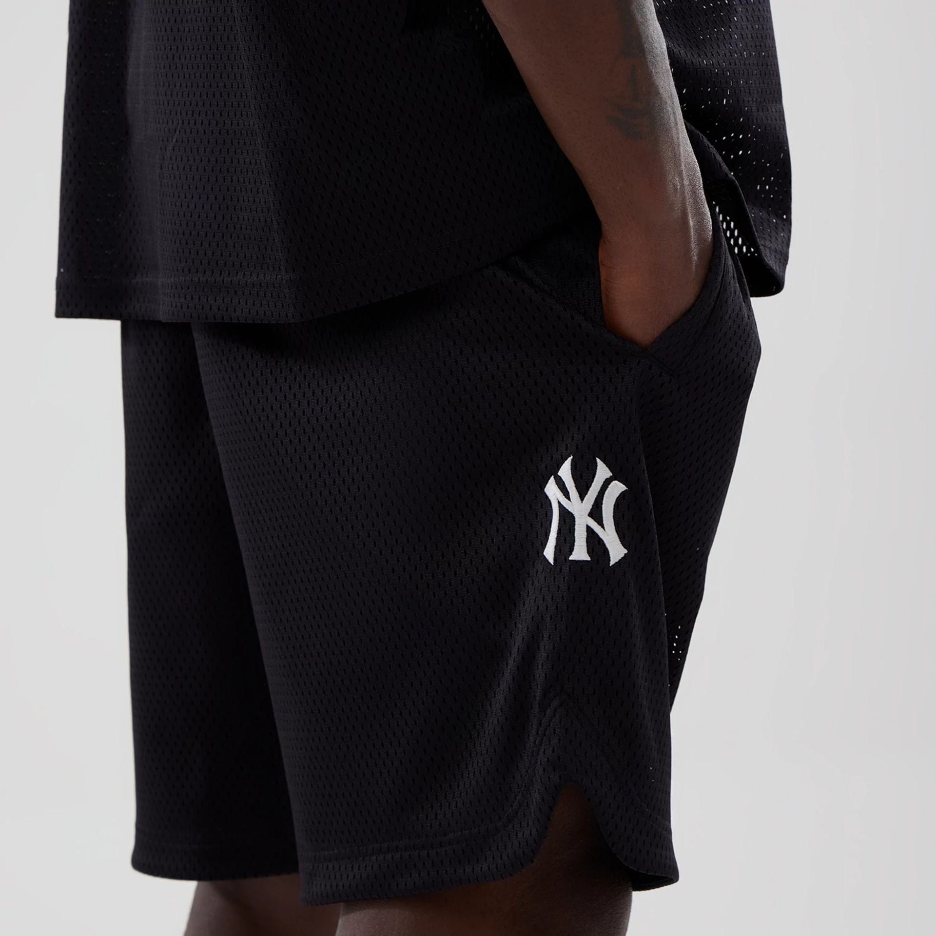 The model is wearing this MLB Mix League New York Yankees Oversized Mesh Shorts in black. 5