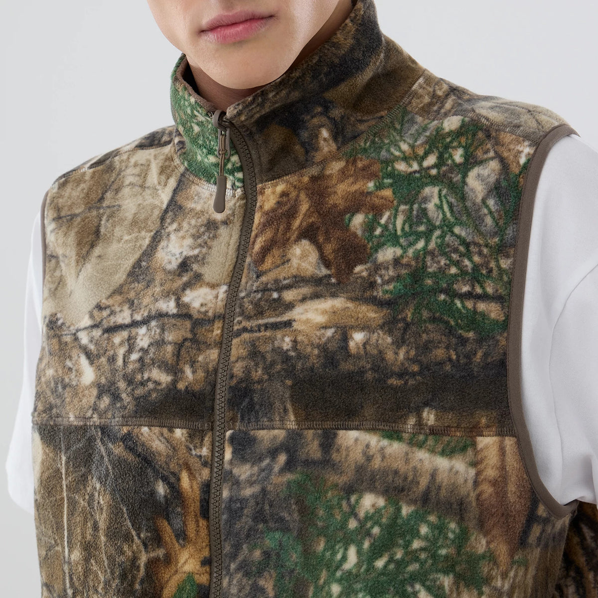 The model is wearing this Thisisneverthat X New Era Revolution Fleece Vest in Real Tree. 3