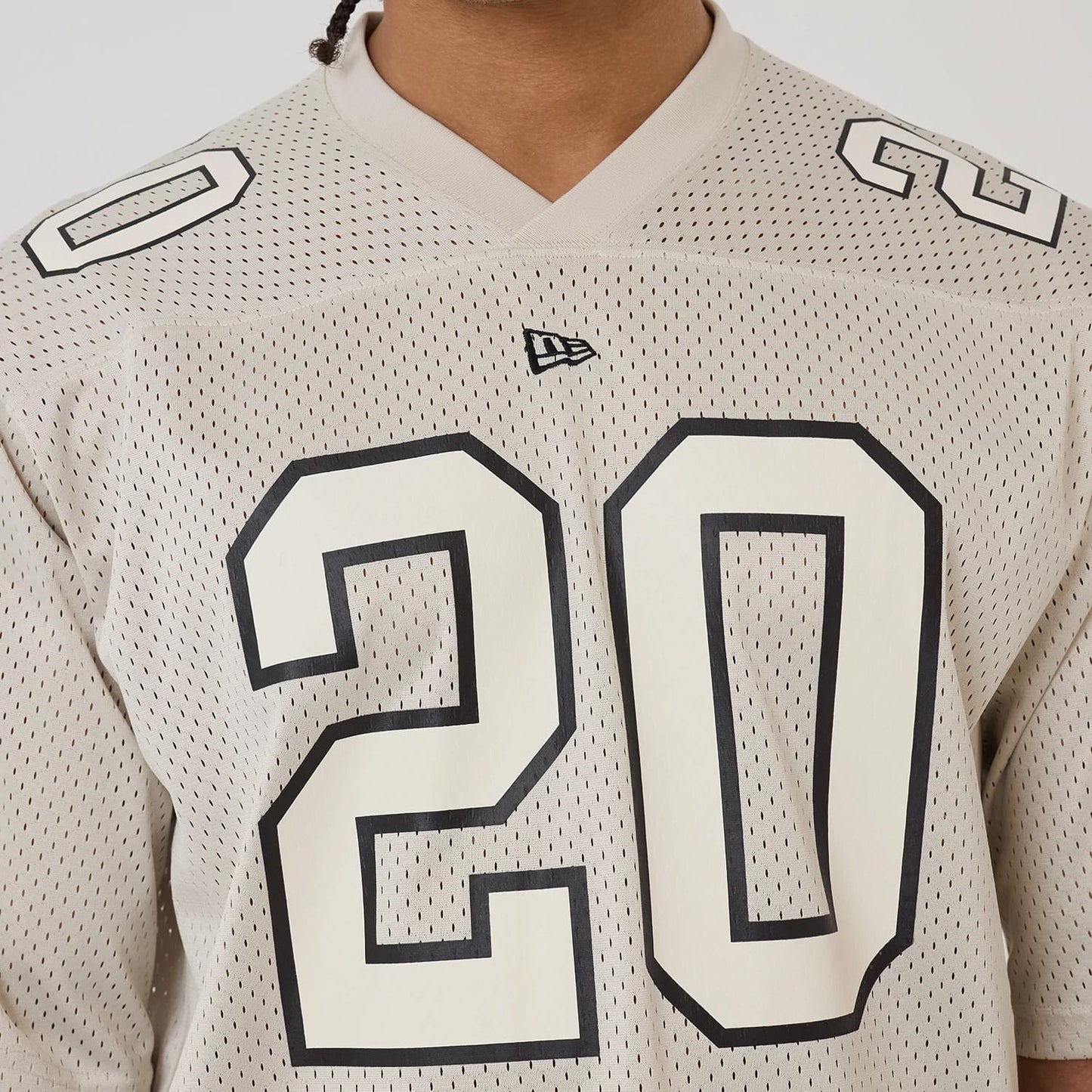 The model is wearing this New Era Mesh Football Short Sleeve Shirt in beige. 4