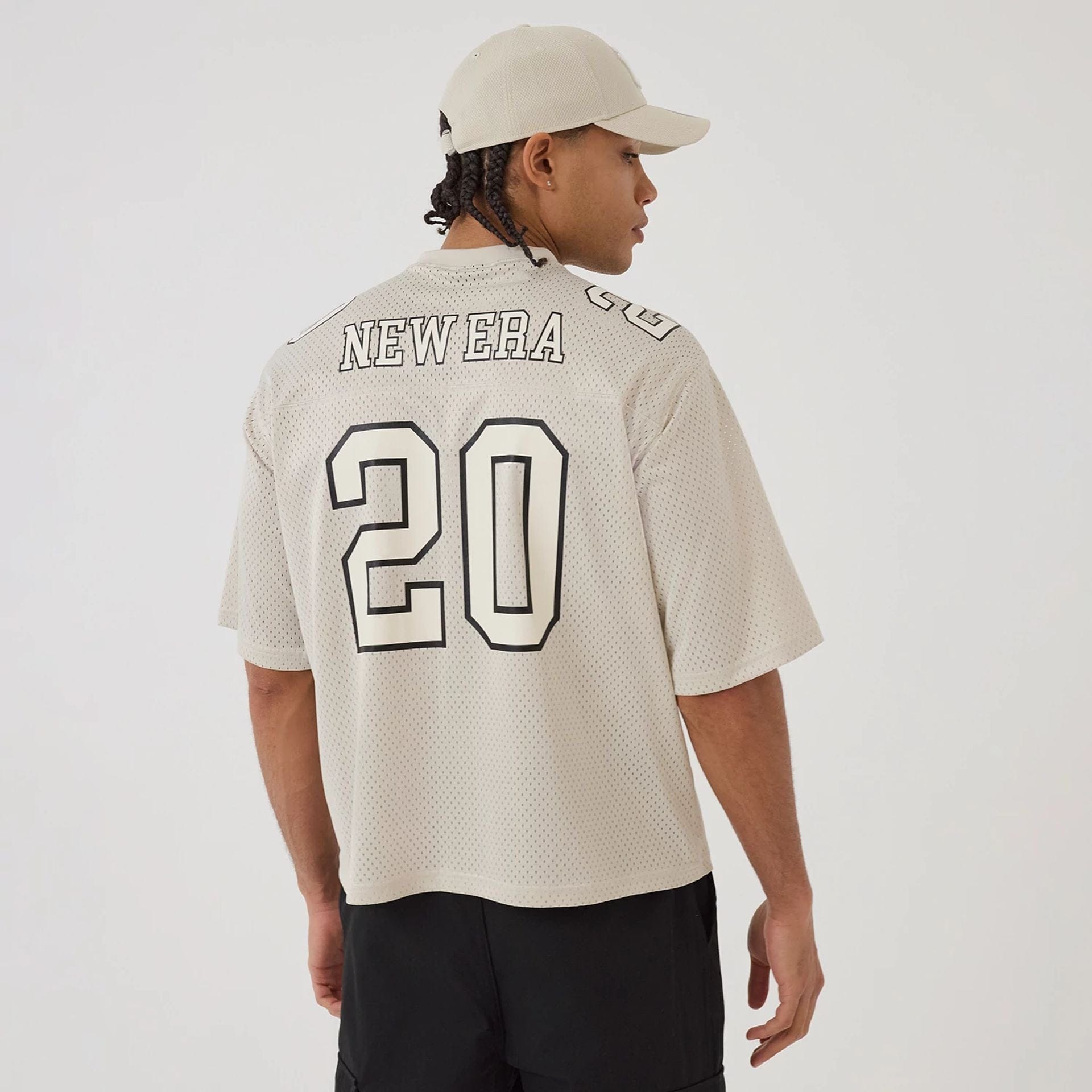 The model is wearing this New Era Mesh Football Short Sleeve Shirt in beige. 2